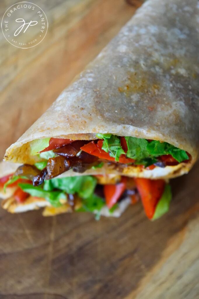 Two halves of a Cajun Chicken Wrap stacked and sitting on a cutting board.