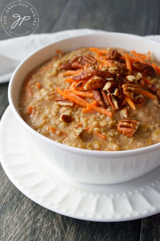 A side view of a white bowl filled with this Carrot Cake Oatmeal and garnished with grated carrots and pecans.