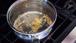 Chopped onions and garlic sautéing in a sauce pot in oil.