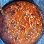 An overhead view looking down into a cast iron dutch oven filled with Dutch Oven Chili.