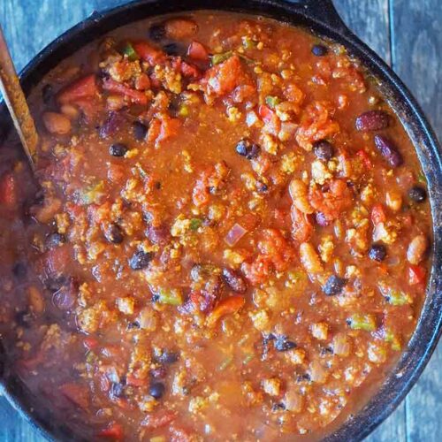 An overhead view looking down into a cast iron dutch oven filled with Dutch Oven Chili.