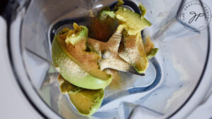 Avocado and spices sitting in a blender cup prior to blending.