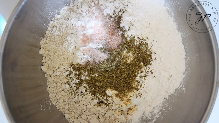 Flour, spices and salt sitting in a stainless steel mixing bowl.