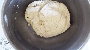 A ball of Oat Flour Pizza Crust dough in a stainless steel mixing bowl.