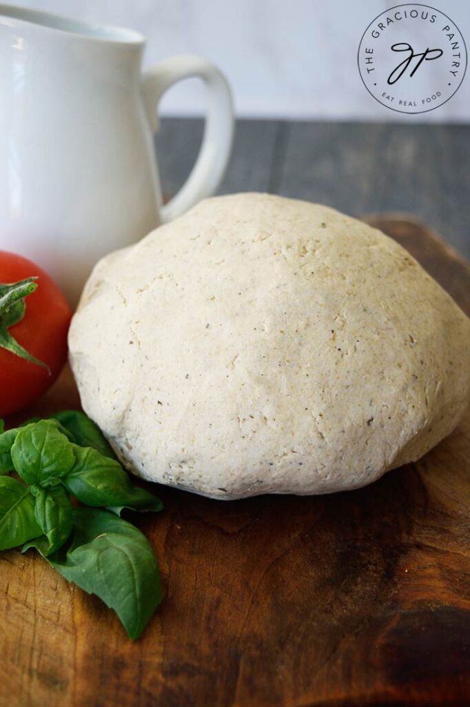 A close up of a ball of oat flour pizza crust dough sitting on a cutting board.