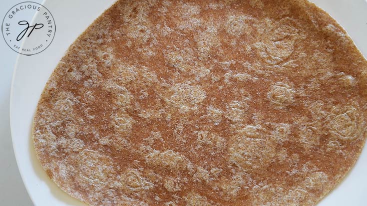 A whole wheat tortilla on a white plate.