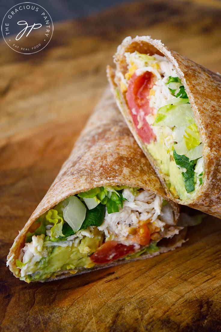 A Ranch Chicken Wrap sliced in half and stacked on a cutting board.