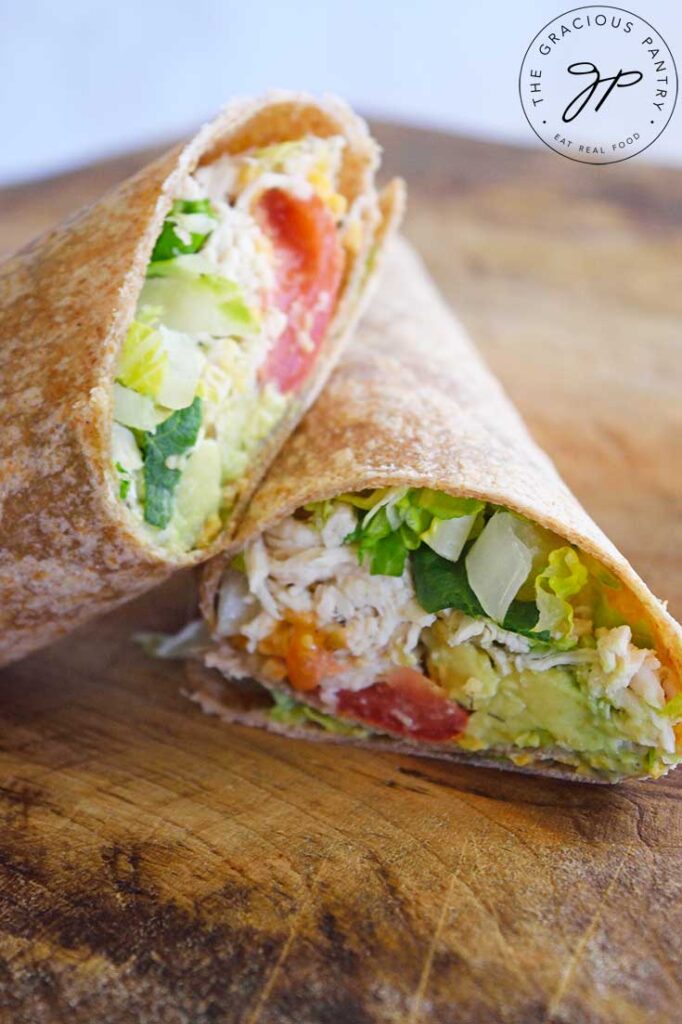 A Ranch Chicken Wrap stacked up on a cutting board with a white background behind it.