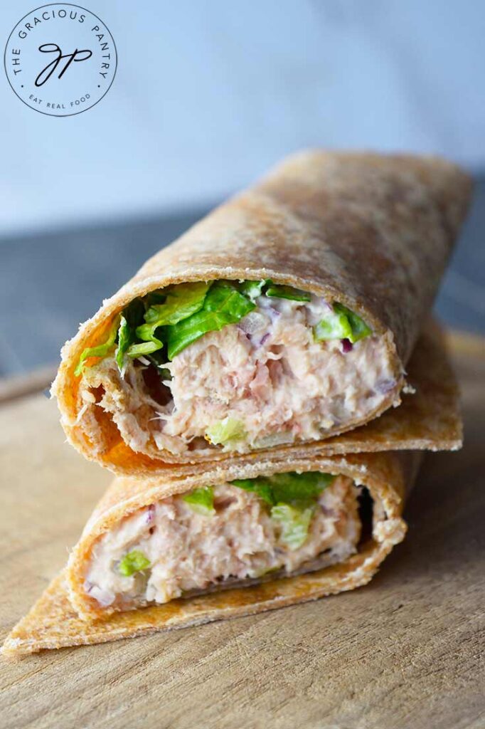A front view of a tuna wrap, cut in half and stacked up on a cutting board.
