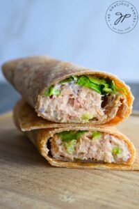 An angled view of a tuna wrap, cut in half and stacked up on a cutting board.