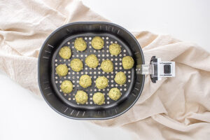 Air fryer falafel balls sitting in an air fryer basket.