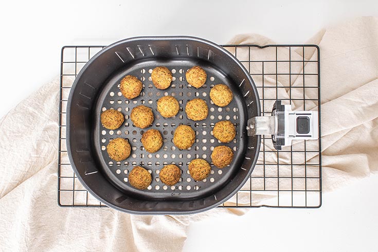 Air fryer falafel balls, just cooked and still sitting in an air fryer basket.