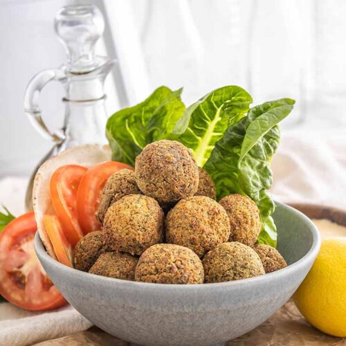 A front view of a gray bowl piled high with falafel balls.