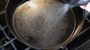 Oil spraying on a cast iron skillet.