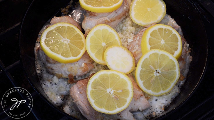 Lemon slices laid over chicken thighs just before going into the oven.