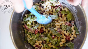 BLT Pasta Salad being tossed with mayo dressing.