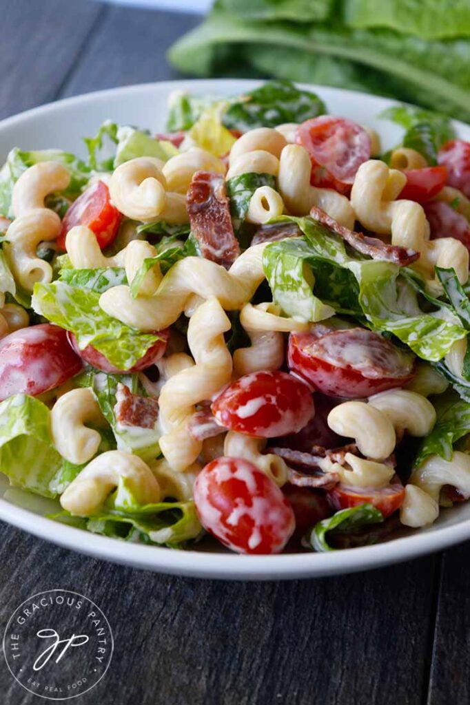 A side view of a white bowl filled with BLT Pasta Salad.