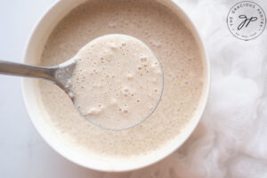 A spoon lifts some just-made batter from the bowl towards the camera.