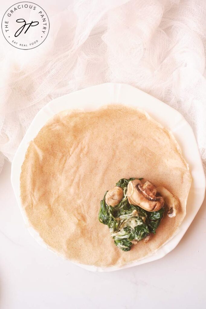 Savory, sautéd mushrooms and spinach with cheese spooned onto an open crepe.