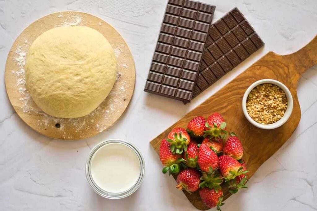 All ingredients for this Chocolate Pizza Recipe collected on a white surface.