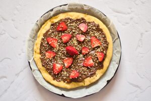 The chocolate pizza topped with strawberries and chopped hazelnuts.