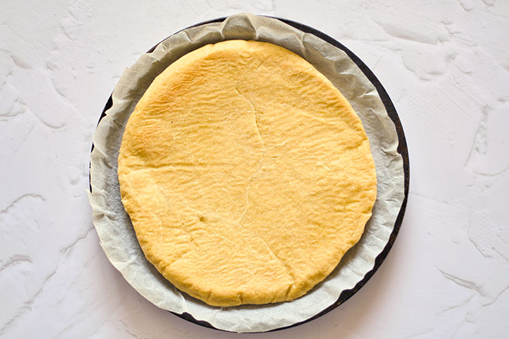 Just baked pizza crust cooling on a pizza pan.