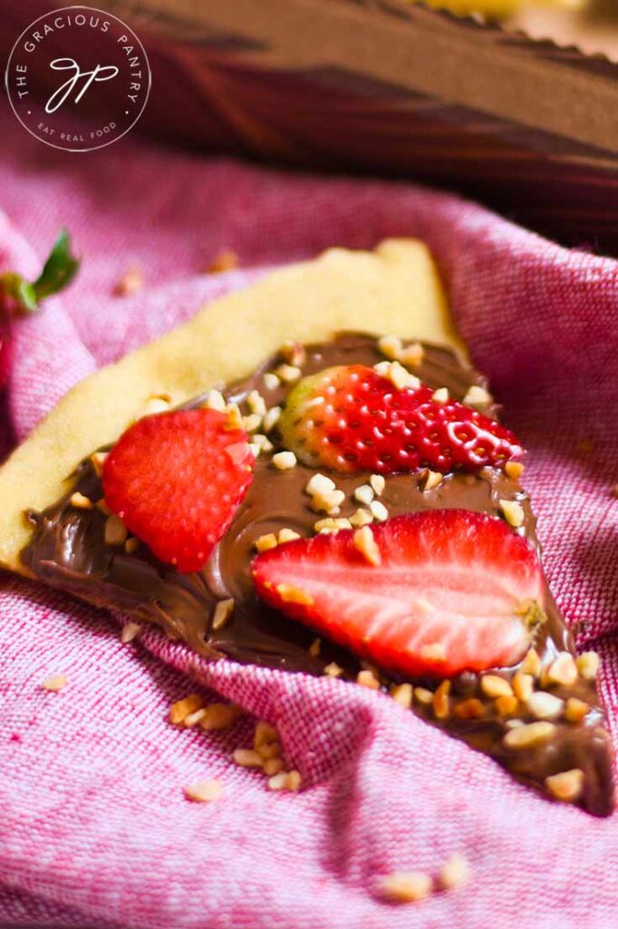 A single slice of chocolate pizza sitting on a pink tablecloth.