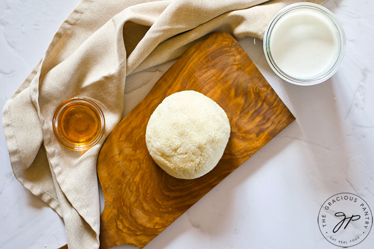 A large coconut dough ball sitting on a cutting board.