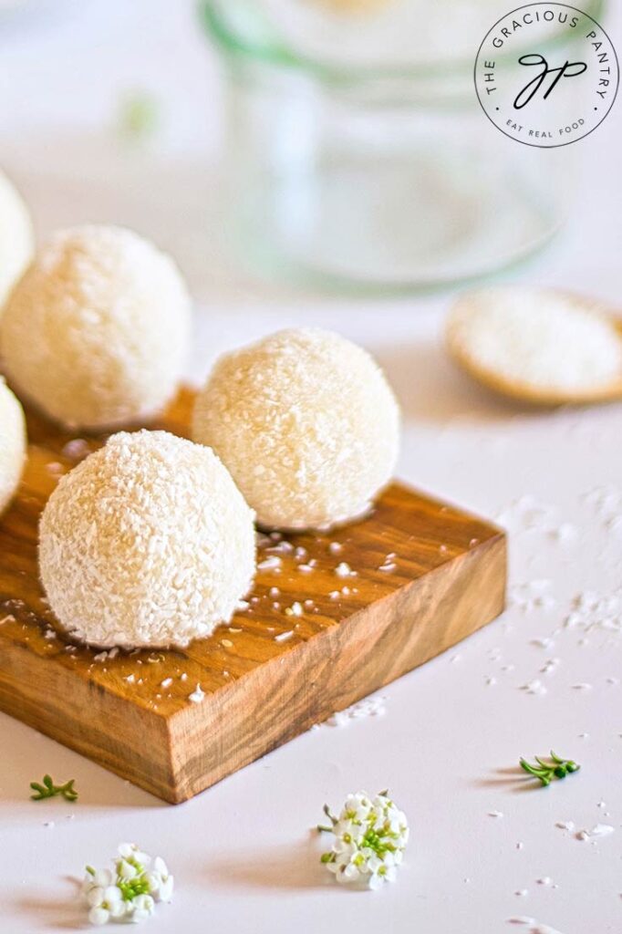 Coconut balls lined up on a cutting board.