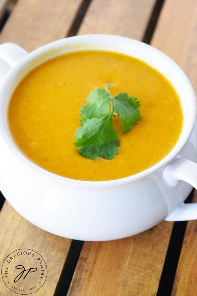 An overhead view looking down on a white crock filled with curried sweet potato soup.