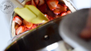 Strawberry sauce being poured over fresh strawberries in a pie crust.