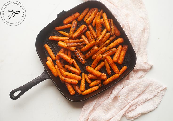 Grilled baby carrots sitting on a grill pan.