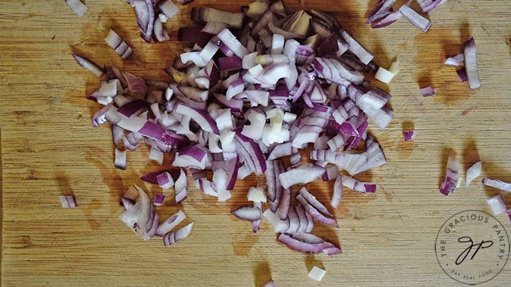 Chopped red onions on a wooden cutting board.