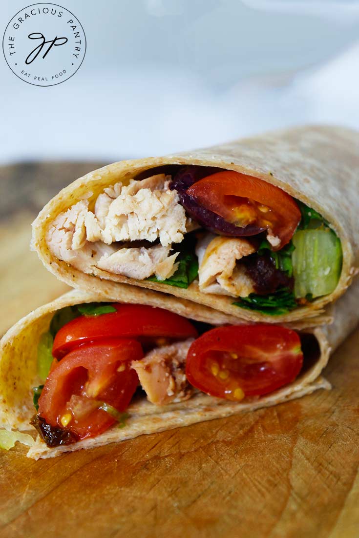 A front view of an italian chicken wrap, cut in half and stacked on a wooden surface.