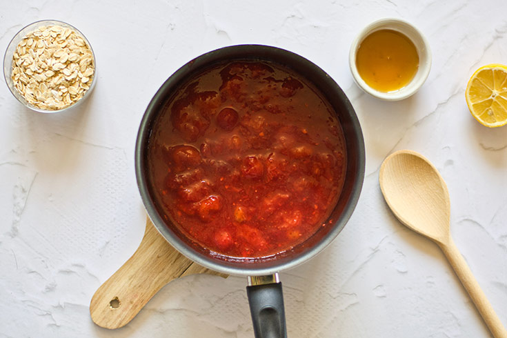 Cooked strawberries cooling in a sauce pot.