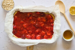 Strawberry filling poured into a baking pan over baked crust.