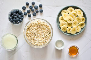 All the ingredients for this Blended Baked Oatmeal Recipe in individual bowls sitting on a white surface.