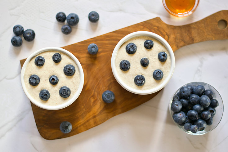 Oatmeal batter poured into ramekins and topped with fresh blueberries.