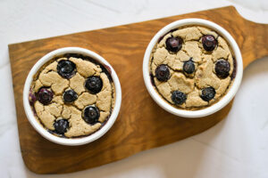 Two baked Blended Baked Oatmeal ramekins sitting on a cutting board.