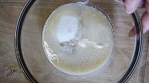 Melted butter with granular sweetener sitting in a mixing bowl.