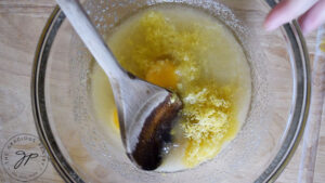 Eggs and lemon zest added to melted butter and sweetener in a mixing bowl.