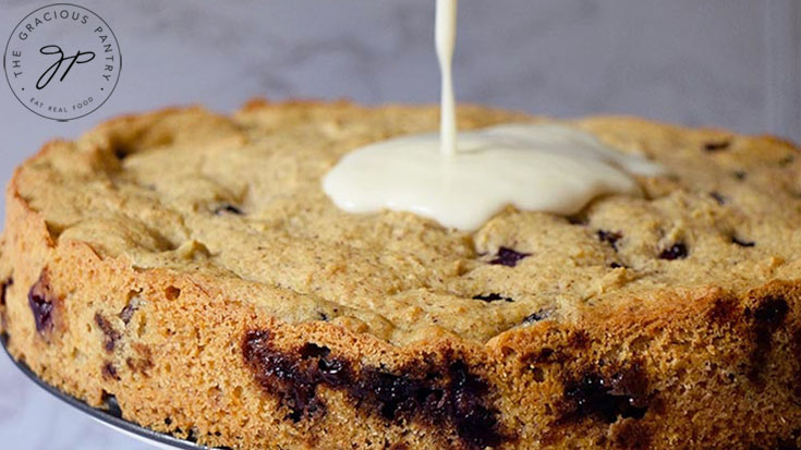 Pouring icing over the top of a baked blueberry cake.
