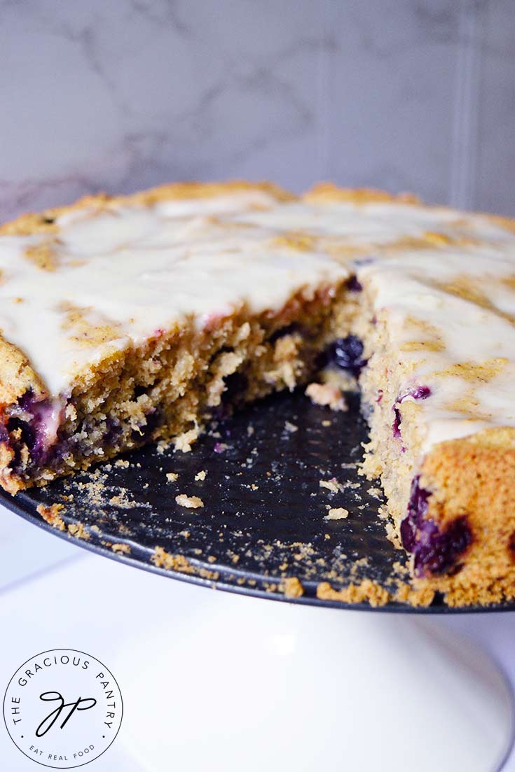 A close up shot of a blueberry cake with a slice removed.