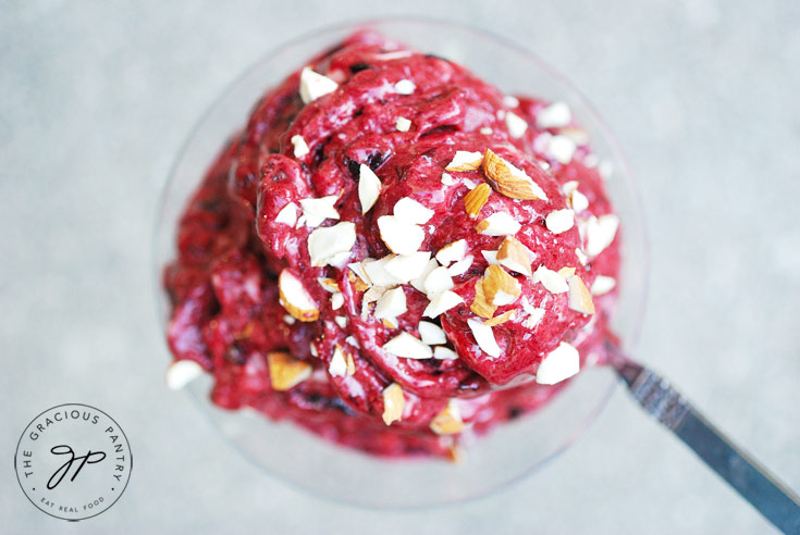 Overhead view looking down into a clear martini glass filled with Cherry Nice Cream and topped with chopped almonds.