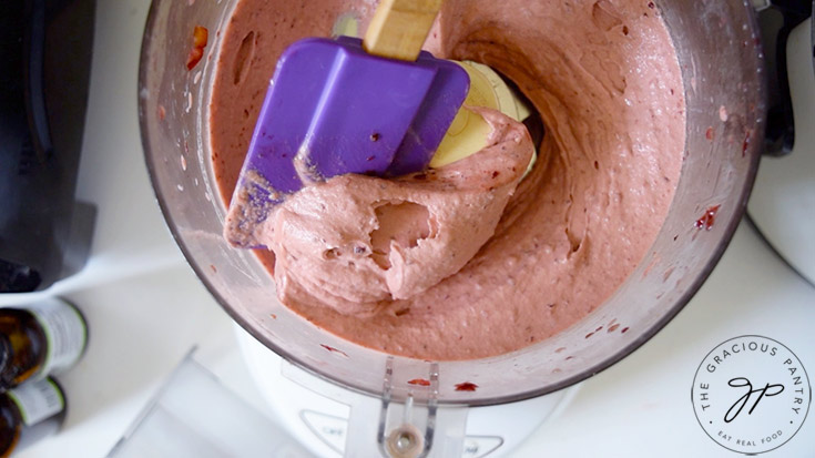Fully blended Cherry Nice Cream being scooped up by a purple, rubber spatula.