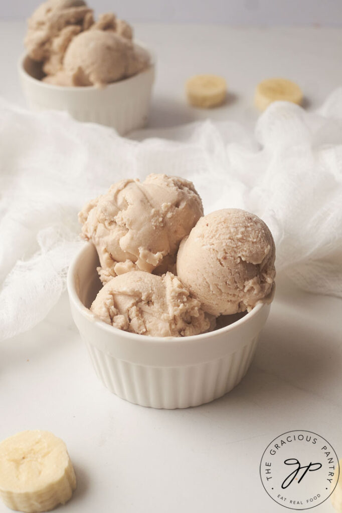 A side view of a white bowl holding three schools of coconut banana ice cream.