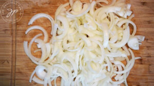 Sliced yellow onions laying on a cutting board.