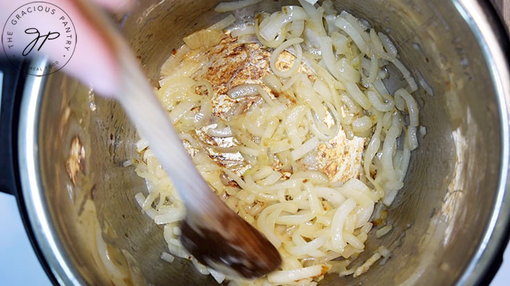 Yellow onion slices being sautéd in an Instant Pot.