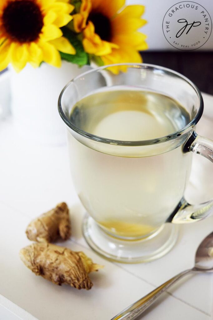 An up close view of a glass mug filled with Fresh Ginger Tea on a serving tray.