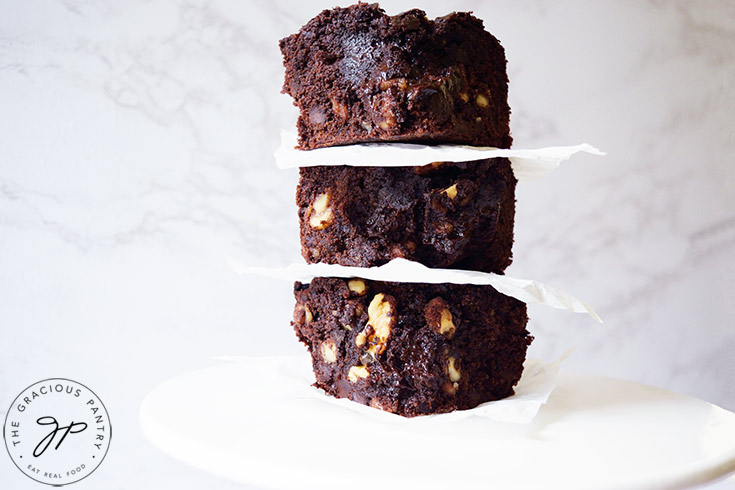 Three oat flour brownies stacked up on a white platter.